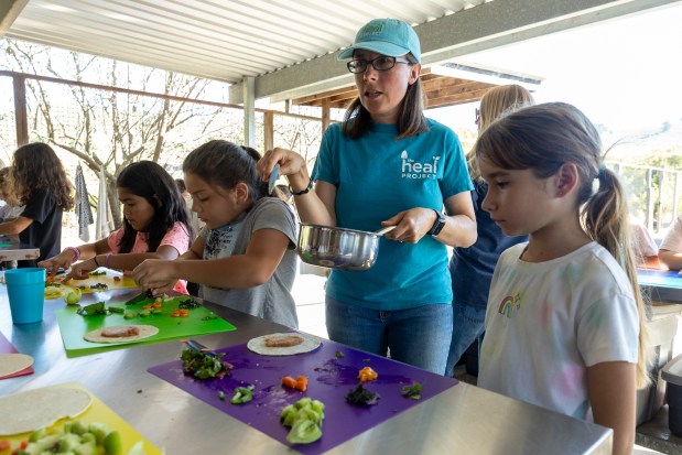 Sara Neale, farm educator at HEAL Project, helps El Granada third graders prepare veggie tacos after harvesting produce on a field trip on Wednesday, Oct. 23, 2024, Half Moon Bay, Calif. (Karl Mondon/Bay Area News Group)