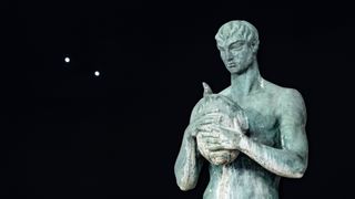 Venus and Jupiter appear very close in the night sky in the foreground statue