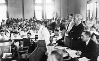 Defense attorney Clarence Darrow leans on a table during Scopes "A monkey" A case in which biology teacher John T. Scopes was prosecuted for teaching evolution to his class. Scopes sits at Darrow's right hand with folded arms. (Getty Images)